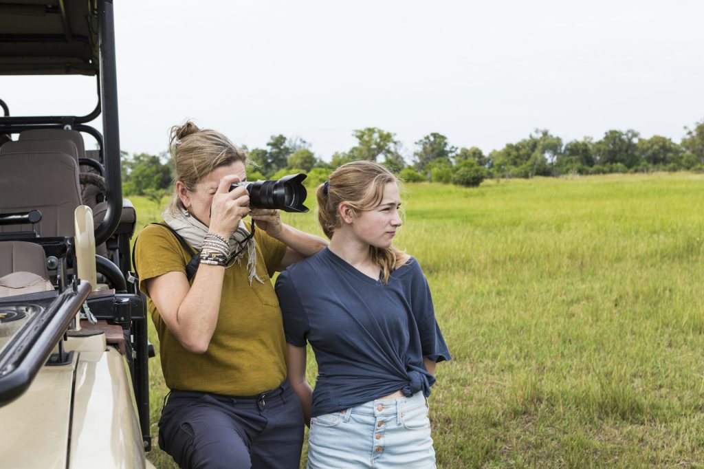 mother photographing with teen daughter near safari vehicle, Botswana