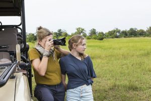 mother photographing with teen daughter near safari vehicle, Botswana